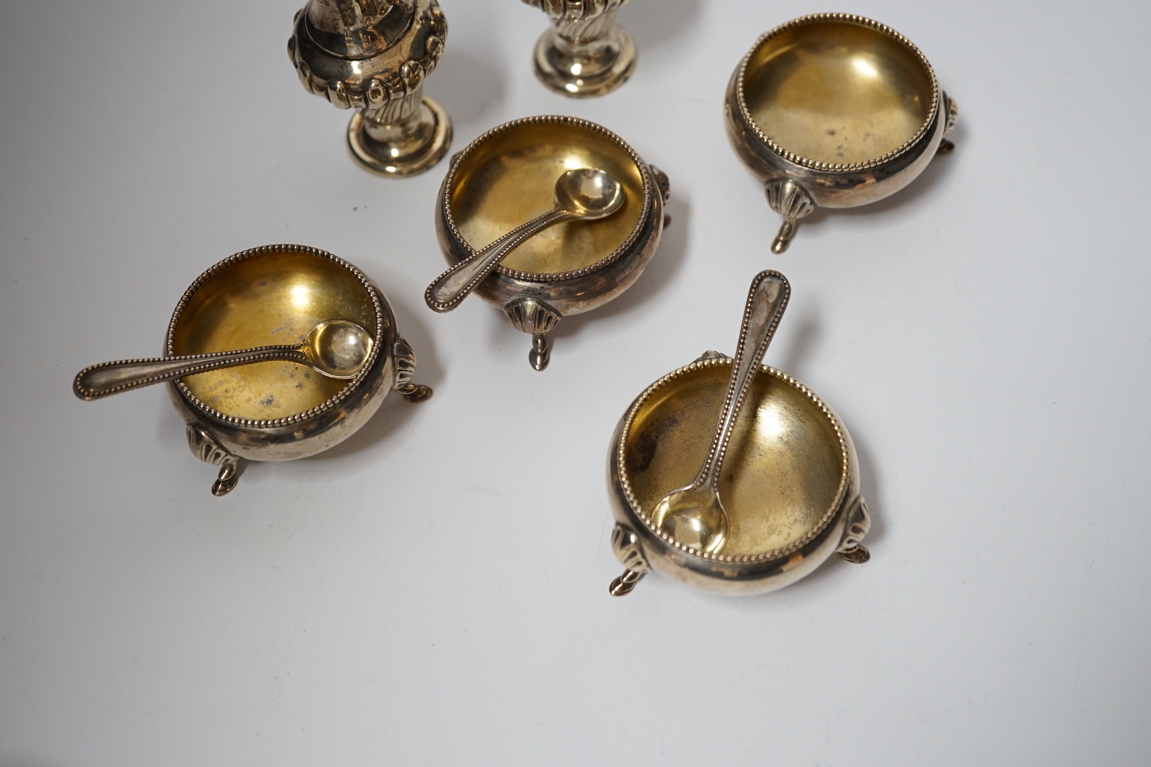 A set of four late Victorian silver bun salts by Hukin & Heath, with four matched spoons and a pair of silver pepperettes